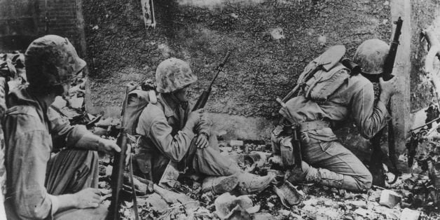 8th June 1945: A group of 6th Division Marines take cover behind a wall during their fight amid the wrecked homes and rubble