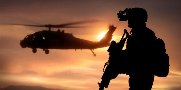 Combat ready special operation forces soldier in an Afghanistan war scene with a black hawk helicopter.