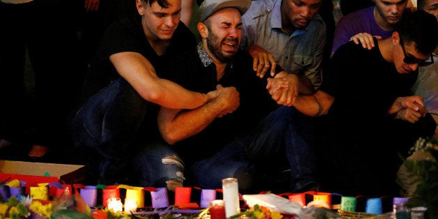 A man sits and cries after taking part in a candlelight memorial service the day after a mass shooting at the Pulse gay night