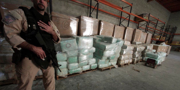 An agent from the U.S. Immigration and Customs Enforcement (ICE) stands guard in front of blocks of marijuana in an industrial building near the Mexican border in Otay Mesa, California November 3, 2010. U.S. border police have found a sophisticated smuggler's tunnel the length of six football fields linking Southern California with Mexico and believed to have been used by drug traffickers, authorities said on Wednesday. Agents also recovered more than 20 tons of marijuana during overnight searches of the tunnel, the border patrol said in a news release. REUTERS/Nelvin C. Cepeda/San Diego Union-Tribune/Pool (UNITED STATES - Tags: POLITICS CRIME LAW SOCIETY)