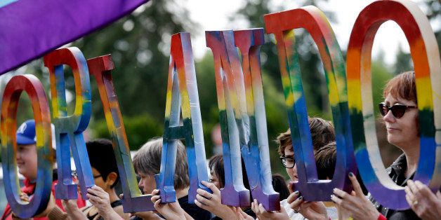 Members of Capital City Pride and others from the LGBT community hold up letters spelling out "Orlando" to honor of the recent shooting at a gay nightclub days earlier before the raising of a rainbow flag in front of the Washington state Capitol Wednesday, June 15, 2016, in Olympia, Wash. The rainbow flag was raised to mark the start of Gay Pride month, and was immediately lowered to half-staff to mark last weekend's mass shooting at a central Florida nightclub. (AP Photo/Elaine Thompson)