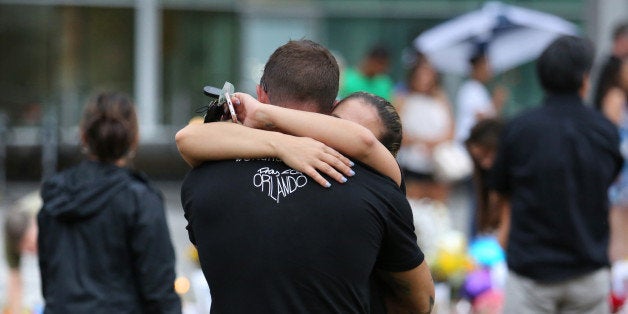 Under a steady drizzle, visitors at the makeshift memorial at the Dr. Phillips Center for the Performing Arts, in downtown Orlando, Fla., mourn the victims of the Pulse massacre on Saturday, June 18, 2016. (Joe Burbank/Orlando Sentinel/TNS via Getty Images)