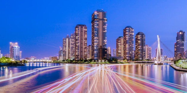 Tokyo cityscape nightview with light trails of houseboat in Tsukishima on Sumida River, Japan.