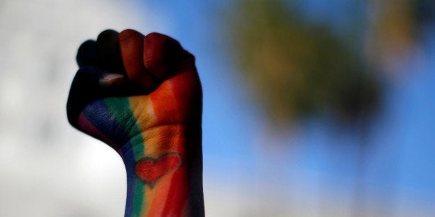Dominique Hernandez holds up her fist painted in the colors of a rainbow, with a heart on her pulse, attends a vigil in memor