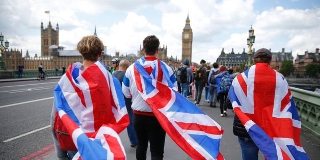 People walk over Westminster Bridge wrapped in Union flags, towards the Queen Elizabeth Tower (Big Ben) and The Houses of Parliament in central London on June 26, 2016. Britain's opposition Labour party plunged into turmoil Sunday and the prospect of Scottish independence drew closer, ahead of a showdown with EU leaders over the country's seismic vote to leave the bloc. Two days after Prime Minister David Cameron resigned over his failure to keep Britain in the European Union, Labour leader Jeremy Corbyn faced a revolt by his lawmakers who called for him, too, to quit. / AFP / Odd ANDERSEN (Photo credit should read ODD ANDERSEN/AFP/Getty Images)