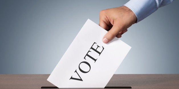 Close up of male hand putting vote into a balot box