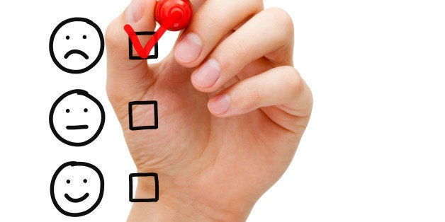 Hand putting check mark with red marker on poor customer service evaluation form.