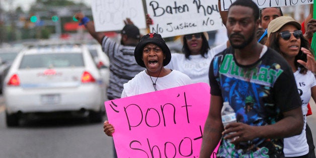 People demonstrate in the street as police cars pass outside the Triple S convenience store in Baton Rouge, La., Wednesday, July 6, 2016. Alton Sterling, 37, was shot and killed outside the store by Baton Rouge police, where he was selling CDs. (AP Photo/Gerald Herbert)