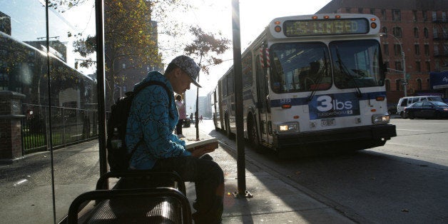 Teenage boy (15-17) at bus stop reading book