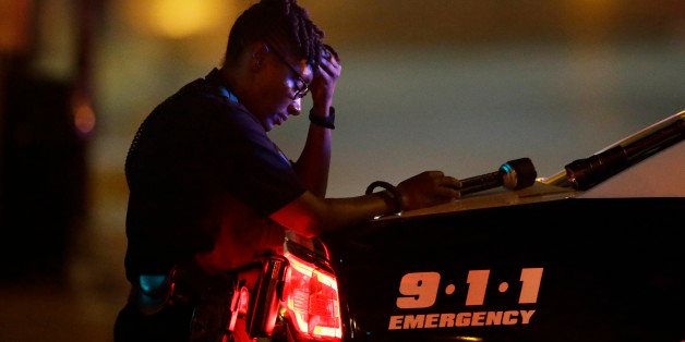 A Dallas police officer, who did not want to be identified, takes a moment as she guards an intersection in the early morning after a shooting in downtown Dallas, Friday, July 8, 2016. At least two snipers opened fire on police officers during protests in Dallas on Thursday night; some of the officers were killed, police said. (AP Photo/LM Otero)