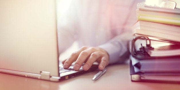 Businessman or designer using laptop computer at desk in office