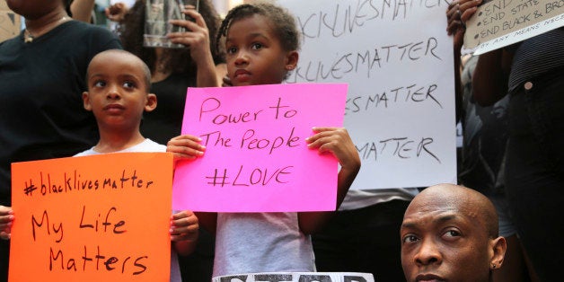 Jashaun Sadler, right, and his twins Malik, left, and Jazlin Sadler listen to speakers during a Black Lives Matter demonstration in New York, Sunday, July 10, 2016. A crowd of about 300 people protested against the shootings of black men by police officers. (AP Photo/Seth Wenig)