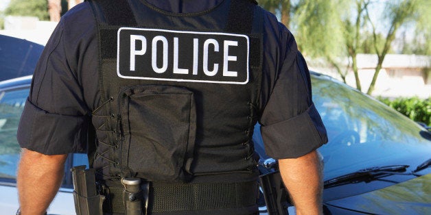 Police officer in bulletproof vest outdoors, back view