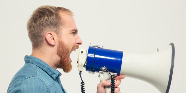 Side view portrait of a casual man yelling into megaphone isolated on a white background