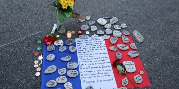This photo taken on July 16, 2016 in Nice shows a make-shift memorial made of France's flag and messages written on stones le