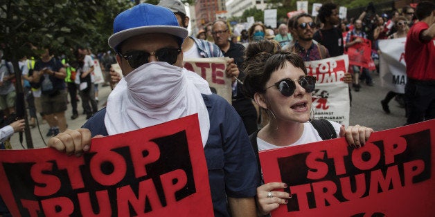 Protesters march while holding 'Stop Trump' signs during a demonstration at the Republican National Convention (RNC) in Cleveland, Ohio, U.S., on Monday, July 18, 2016. Republican factions trying to stop Donald Trump's nomination noisily disrupted a vote on party convention rules, displaying the fissures in the party on the first day of its national convention. Photographer: Victor J. Blue/Bloomberg via Getty Images