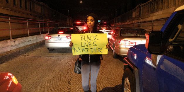 OAKLAND, CA - DECEMBER 13: A protester marches through stopped cars while carrying a sign that reads 'Black Lives Matter' in the Alameda-Oakland tunnel during a 'Millions March' demonstration protesting the killing of unarmed black men by police on December 13, 2014 in Oakland, California. The march was one of many held nationwide. (Photo by Elijah Nouvelage/Getty Images)
