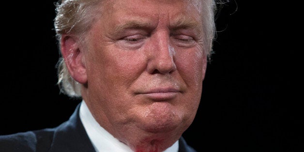 Republican presidential candidate Donald Trump bows his head during a prayer at a town hall with vice presidential candidate