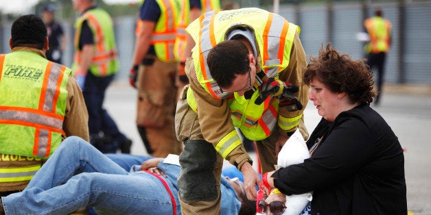 First responders work with volunteers pretending to be victims in a simulated airplane crash during a full-scale emergency preparedness exercise at Washington's Reagan National Airport in Arlington, Virginia, September 21, 2013. The exercise, which the airport is required to complete every three years, included a river rescue, support helicopters, a trainer aircraft that was lit on fire, 150 volunteer role players and more than 50 responding vehicles from 13 surrounding fire departments. REUTERS/Jonathan Ernst (UNITED STATES - Tags: DISASTER TRANSPORT TPX IMAGES OF THE DAY)