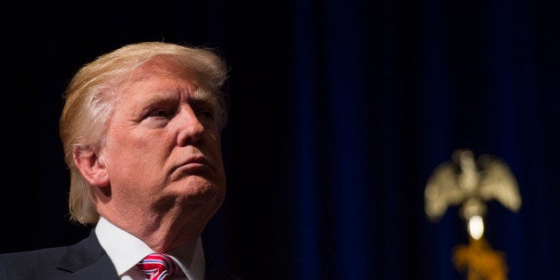 Republican presidential nominee Donald Trump listens while his son Eric Trump speaks during a campaign event at Briar Woods High School August 2, 2016, in Ashburn, Virginia. / AFP / MOLLY RILEY (Photo credit should read MOLLY RILEY/AFP/Getty Images)