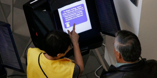 An election worker shows a voter how to use an electronic voting machine at the Denver Elections Division headquarters in downtown Denver October 25, 2012. Early voting began in swing state Colorado on Monday. REUTERS/Rick Wilking (UNITED STATES - Tags: POLITICS ELECTIONS USA PRESIDENTIAL ELECTION)