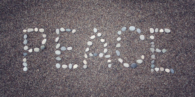 'Peace' word written with pebbles on the sand. Aged photo. 'Peace' word made by small stones on the beach. Word on the sand -
