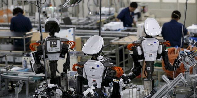 Humanoid robots work side by side with employees in the assembly line at a factory of Glory Ltd., a manufacturer of automatic change dispensers, in Kazo, north of Tokyo, Japan, July 1, 2015. Japanese firms are ramping up spending on robotics and automation, responding at last to premier Shinzo Abe's efforts to stimulate the economy and end two decades of stagnation and deflation. Picture taken July 1, 2015. REUTERS/Issei Kato