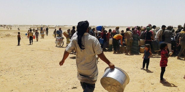 In this Tuesday, June 28, 2016 photo, Syrian refugees gather for water at Ruqban border camp in northeast Jordan. Syrian refugees and international aid officials say little water and no food has reached 64,000 Syrian refugees stranded in the desert since Jordan sealed its border in response to a suicide attack on June 21, 2016. (AP Photo)