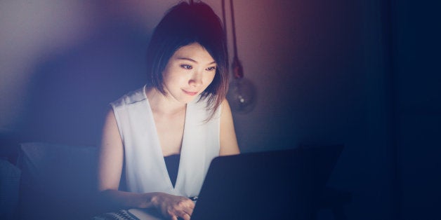 Young woman using laptop on bed