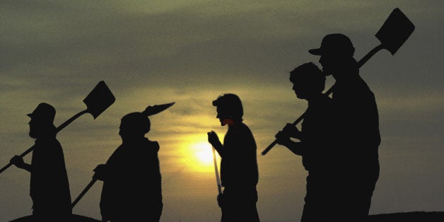 Silhouette of construction workers carrying shovels