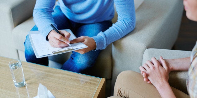 Male psychologist making notes during psychological therapy