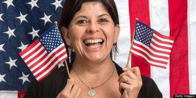 Happy hispanic woman posing waving US flags with a US flag in the background