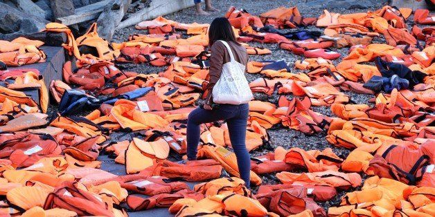 TOPSHOT - A woman walks through life jackets which have been collected from the beaches of Chios, Greece and used by adults and children,on display at the Brooklyn Bridge park ahead of next week's UN Summit for Refugees and Migrants in New York on September 16,2016. / AFP / KENA BETANCUR (Photo credit should read KENA BETANCUR/AFP/Getty Images)
