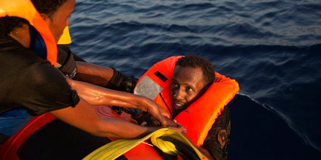 A migrant from Eritrea is helped after jumping into the water from a crowded wooden boat during a rescue operation in the Med