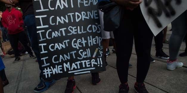 TOPSHOT - Protesters hold signs during a demonstration against police brutality in Charlotte, North Carolina, on September 21, 2016, following the shooting of Keith Lamont Scott the previous day.A protester shot during a second night of unrest in Charlotte, North Carolina was critically wounded, the city said, after earlier reporting that the person had died. / AFP / NICHOLAS KAMM (Photo credit should read NICHOLAS KAMM/AFP/Getty Images)