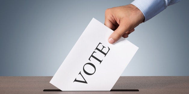 Close up of male hand putting vote into a balot box