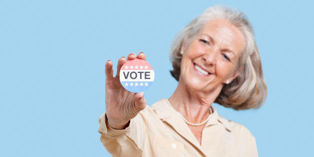 Portrait of senior woman holding an election badge against blue background