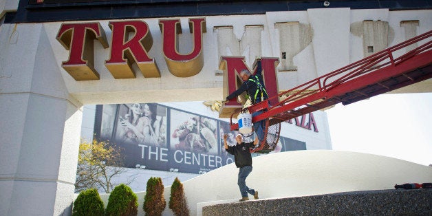 Jim Williams, of Calvi Electric, lowers the letter 'M' from the signage of Trump Plaza Casino to his co-worker Steven Nordaby in Atlantic City, New Jersey October 6, 2014. Workers began removing the large letters spelling out the Trump name from the shuttered Trump Plaza casino in Atlantic City on Monday after real-estate mogul Donald Trump sued to end a licensing deal that allowed the casino owners to use his name. Trump, who has emblazoned his name across properties in various U.S. cities, sued in August to have his name taken off the Trump Plaza, which closed last month, and the nearby Trump Taj Mahal, which is on the verge of closing. REUTERS/Mark Makela (UNITED STATES - Tags: BUSINESS SOCIETY TRAVEL)