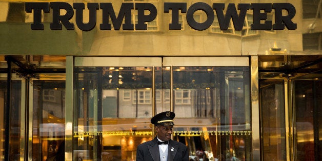 NEW YORK, NEW YORK - SEPTEMBER 29: A doorman stands at the entrance of Trump Tower as protestors rally against Republican pre