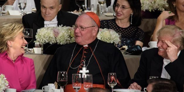 Democratic presidential nominee Hillary Clinton (L) and Republican presidential nominee Donald Trump (R) look to Timothy Cardinal Dolan, Archbishop of New York, during the Alfred E. Smith Memorial Foundation Dinner at Waldorf Astoria October 20, 2016 in New York, New York / AFP / Brendan Smialowski (Photo credit should read BRENDAN SMIALOWSKI/AFP/Getty Images)