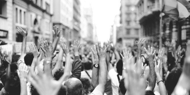 Peoples with hands raised gathered on street.