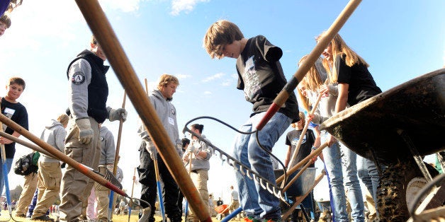 Hundreds of Americorps volunteers, volunteers for Outdoor Colorado and eighth-graders at Hamilton Middle School work together to construct a new quarter-mile walking trail around the school. Hayden Rastall, 13, center, pulled his arms into his shirt to keep warm and jumps up and down on the newly laid path to help tamp it down. While building the track, students and volunteers planted trees and flowers to improve the landscapes of Hamilton and neighboring Holm Elementary. Kathryn Scott Osler, The Denver Post (Photo By Kathryn Scott Osler/The Denver Post via Getty Images)