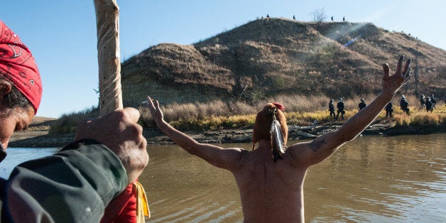 People protest against the building of a pipeline on the Standing Rock Indian Reservation while police officers stand on the