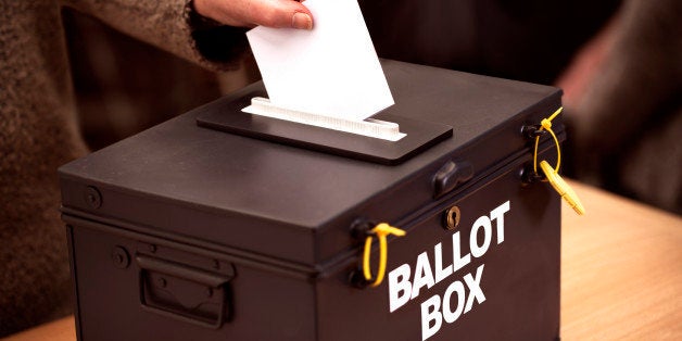 Person places their vote in a ballot box at a polling station.