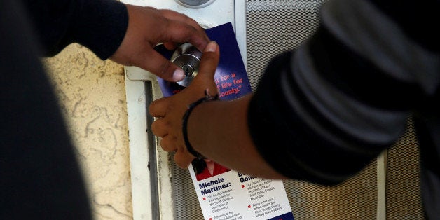 Juan Munoz, 18, and America Najera, 32, of the Democratic Party of Orange County leave a door hanger featuring an image of Donald Trump as they canvass a neighborhood ahead of the California Primary election in Santa Ana, California May 15, 2016. Picture taken May 15, 2016. REUTERS/Patrick T. Fallon