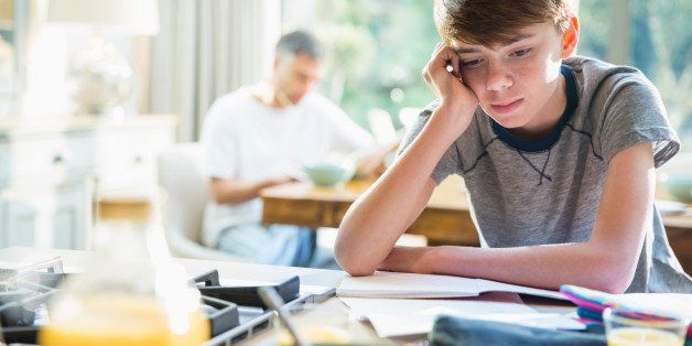 Frustrated boy doing homework at breakfast