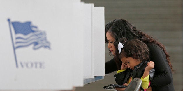 Betsy Argueta holds her daughter Isabella, 2, as she votes in the U.S. presidential election at the National Guard Armory in