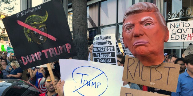 Protesters hold banners during a rally outside the CNN studios, in opposition to President-elect Donald Trump, in the Hollywood section of Los Angeles on Sunday, Nov .13, 2016. (AP Photo/Damian Dovarganes)