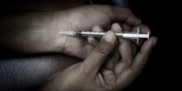 Close-up on the floor of the syringe with the drug. In the background, a women drug addict.