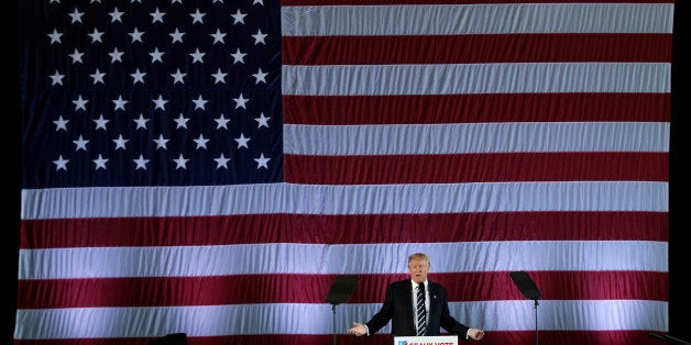 U.S. President-elect Donald Trump speaks beneath a giant American Flag during a "Thank You USA" tour rally in Baton Rouge, Louisiana, U.S., December 9, 2016. REUTERS/Mike Segar